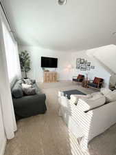 Living area featuring light colored carpet and baseboards