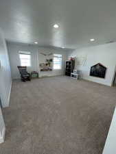Living area with carpet flooring, a textured ceiling, and recessed lighting