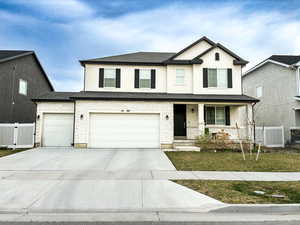 View of front of property with stone siding, a porch, stucco siding, and concrete driveway