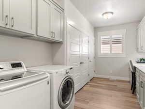 Laundry area with cabinet space, light wood-style flooring, and independent washer and dryer