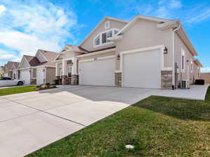 View of front of home with concrete driveway, stucco siding, stone siding, a residential view, and an attached garage