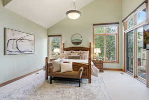Bedroom featuring lofted ceiling, access to exterior, and light colored carpet