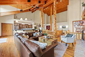Living area with light wood-style floors, a high wooden beamed ceiling, and ceiling fan