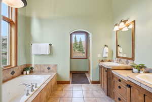 Bathroom featuring double vanity, a garden tub, and light tile patterned flooring