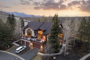 View of front facade featuring asphalt driveway, an attached garage, a chimney, a shingled roof, and a deck with mountain view