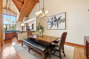 Dining space with a high wood beamed ceiling, suspended lighting, and light wood-style floors