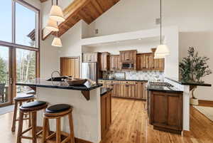 Kitchen featuring a kitchen breakfast bar, wood finish cabinetry, a kitchen island with sink, stainless steel appliances, and a peninsula
