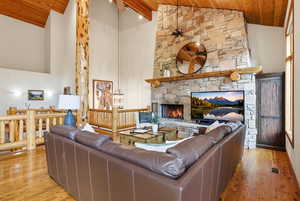 Living room featuring a vaulted wood ceiling, light wood-style flooring, a fireplace, and ceiling fan