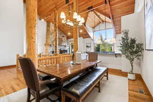 Dining area featuring suspended lighting, light wood finished floors, a high wooden beamed ceiling, and a fireplace