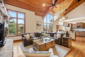 Living area featuring light wood finished floors, a vaulted wooden ceiling, ceiling fan, recessed lighting, and a fireplace