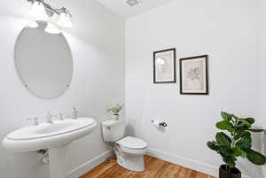 Half bathroom with toilet and light wood-style floors
