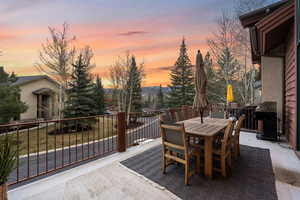 Deck at dusk featuring area for grilling, outdoor dining space, and a patio area