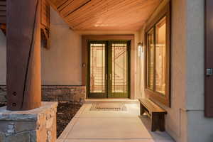 Entrance to property featuring french doors, stone siding, stucco siding, and a patio