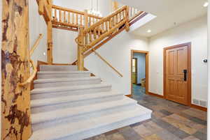 Stairway featuring stone tile flooring, a high ceiling, and a chandelier