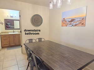 Downstairs bathroom off the dining room with light tile patterned floors and suspended lighting