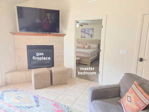 Living area featuring a fireplace, a ceiling fan, and light tile patterned flooring