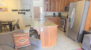 Kitchen with glass insert cabinets, stainless steel appliances, light tile patterned floors, light granite counters, and wood finish cabinets