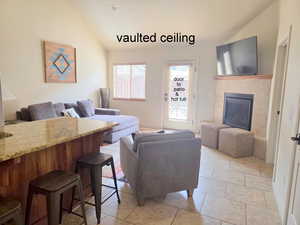 Living area featuring lofted ceiling, light tile patterned floors, and a gas fireplace