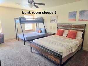 Bunk bedroom with queen bed carpet flooring and ceiling fan