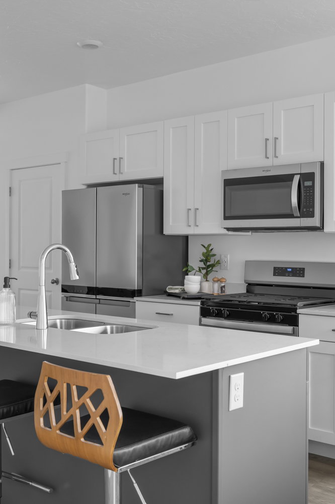 Kitchen featuring white cabinets, stainless steel appliances, light stone countertops, and a kitchen breakfast bar