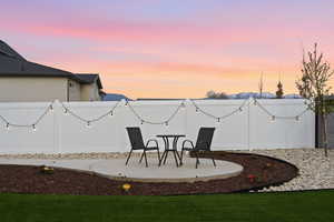 Yard at dusk with a fenced backyard and a patio