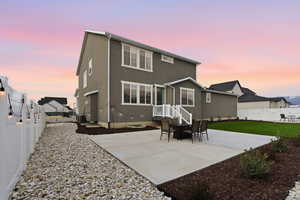 Back of house at dusk with a patio area, a fenced backyard, and stucco siding