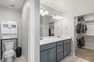 Bathroom with a walk in closet, double vanity, and light marble finish flooring