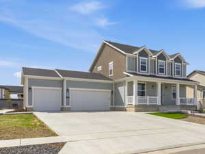 View of front of home featuring a porch, an attached garage, concrete driveway, and a residential view