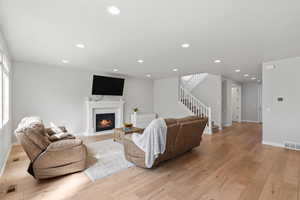 Living room with a glass covered fireplace, light wood-type flooring, and recessed lighting
