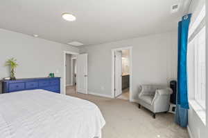 Bedroom featuring light colored carpet and ensuite bath