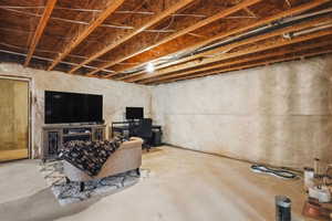 Unfinished below grade area with a desk and a fireplace