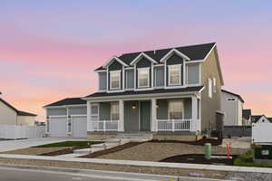 View of front of house featuring covered porch, driveway, and a garage