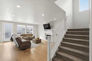 Living room featuring light wood finished floors, a fireplace, and recessed lighting