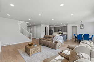 Living area with light wood finished floors and recessed lighting