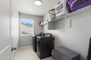 Laundry room featuring light marble finish flooring and washer and clothes dryer