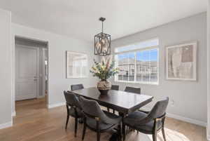 Dining room with light wood-type flooring and a chandelier