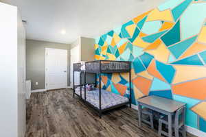 Bedroom featuring an accent wall and dark wood-style flooring