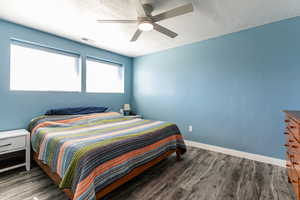 Bedroom with dark wood-style floors, a textured ceiling, and a ceiling fan