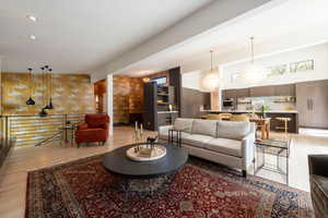 Living room featuring suspended lighting, light wood finished floors, wallpapered walls, and a high ceiling
