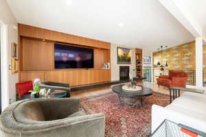 Living area featuring wood finished floors, built in shelves, a fireplace, vaulted ceiling, and recessed lighting