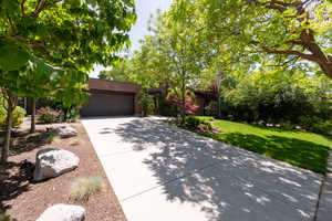 View of front facade featuring an attached garage, concrete driveway, and a front yard