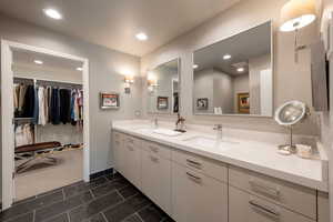 Bathroom with double vanity, a spacious closet, and recessed lighting