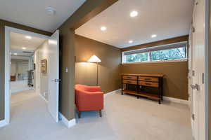 Living area with light carpet and recessed lighting