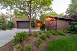 Mid-century inspired home with brick siding, an attached garage, and concrete driveway
