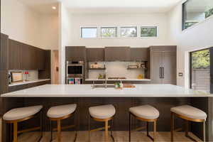 Kitchen featuring dark wood finish cabinetry, a high ceiling, a breakfast bar, and stainless steel appliances