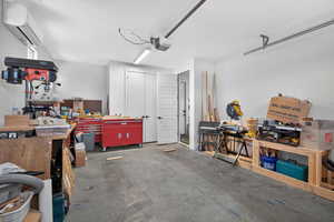 Garage with a workshop area, a wall mounted mini split, and a garage door opener