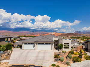 View of front of home with stucco siding, a mountain view, concrete driveway, an attached garage, and a residential view