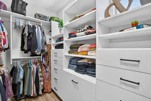 Walk in closet with light wood finished floors