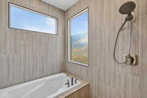 Full bath featuring a whirlpool tub, tile walls, and tiled shower