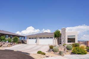 View of front facade featuring stucco siding, driveway, and an attached garage